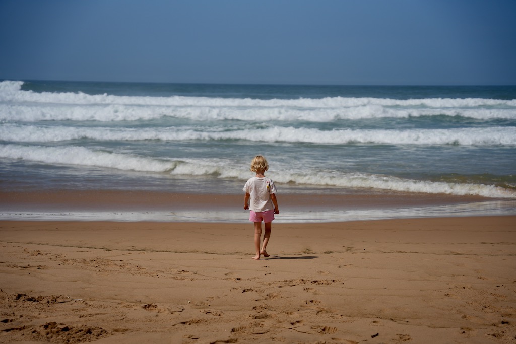 Kind vor der Brandung am Praia do Castelejo
